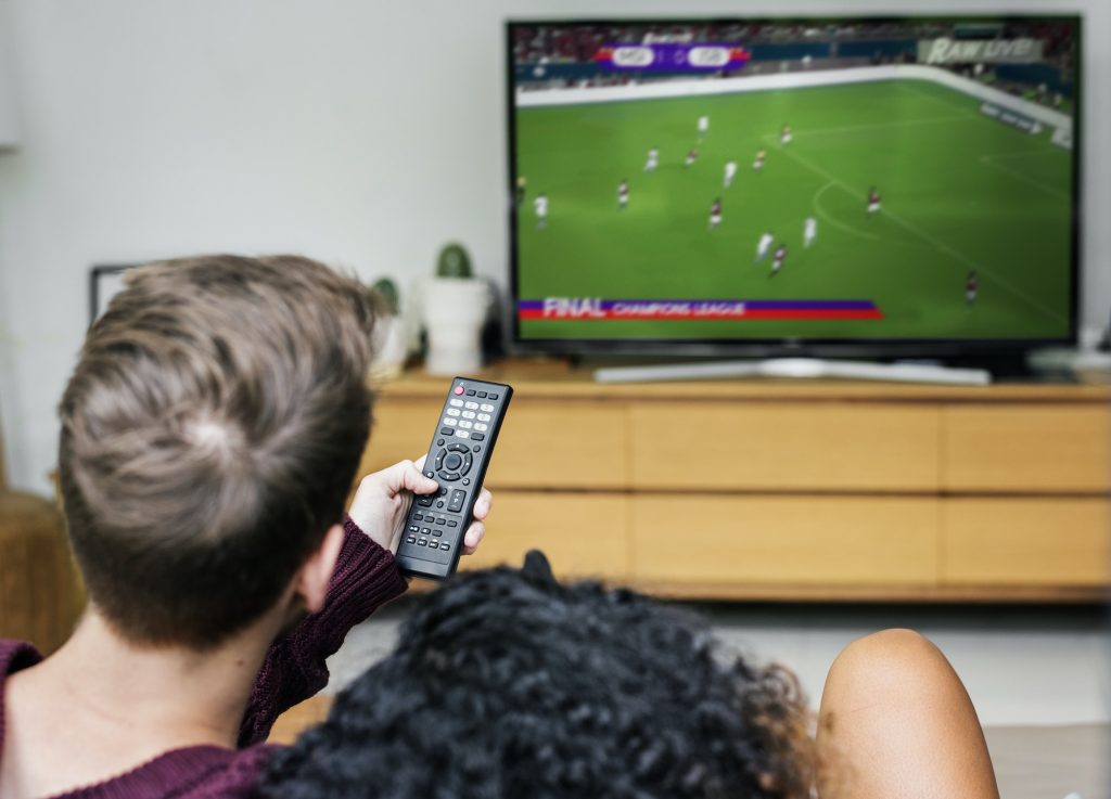 Utilisateur contrôlant une télévision intelligente avec une télécommande. Profitez de votre abonnement IPTV en France pour accéder à une variété de contenus sur votre téléviseur intelligent.